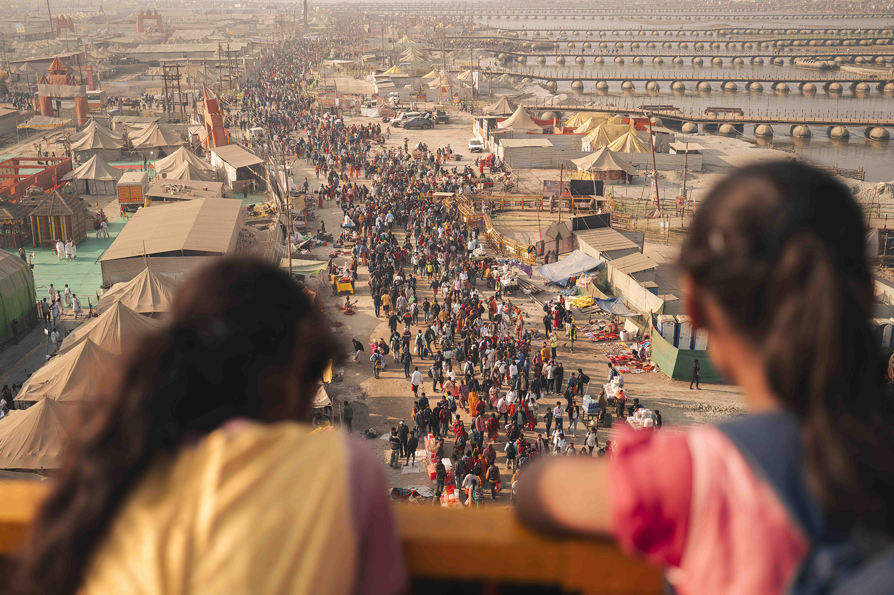 Two people on a balcony looking down upon a parade.
