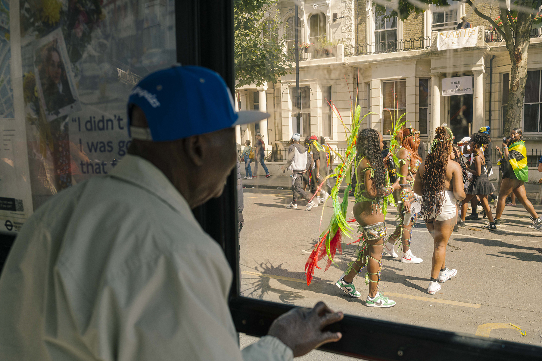 Person looking through window towards participants at the Notting Hill Carnival.