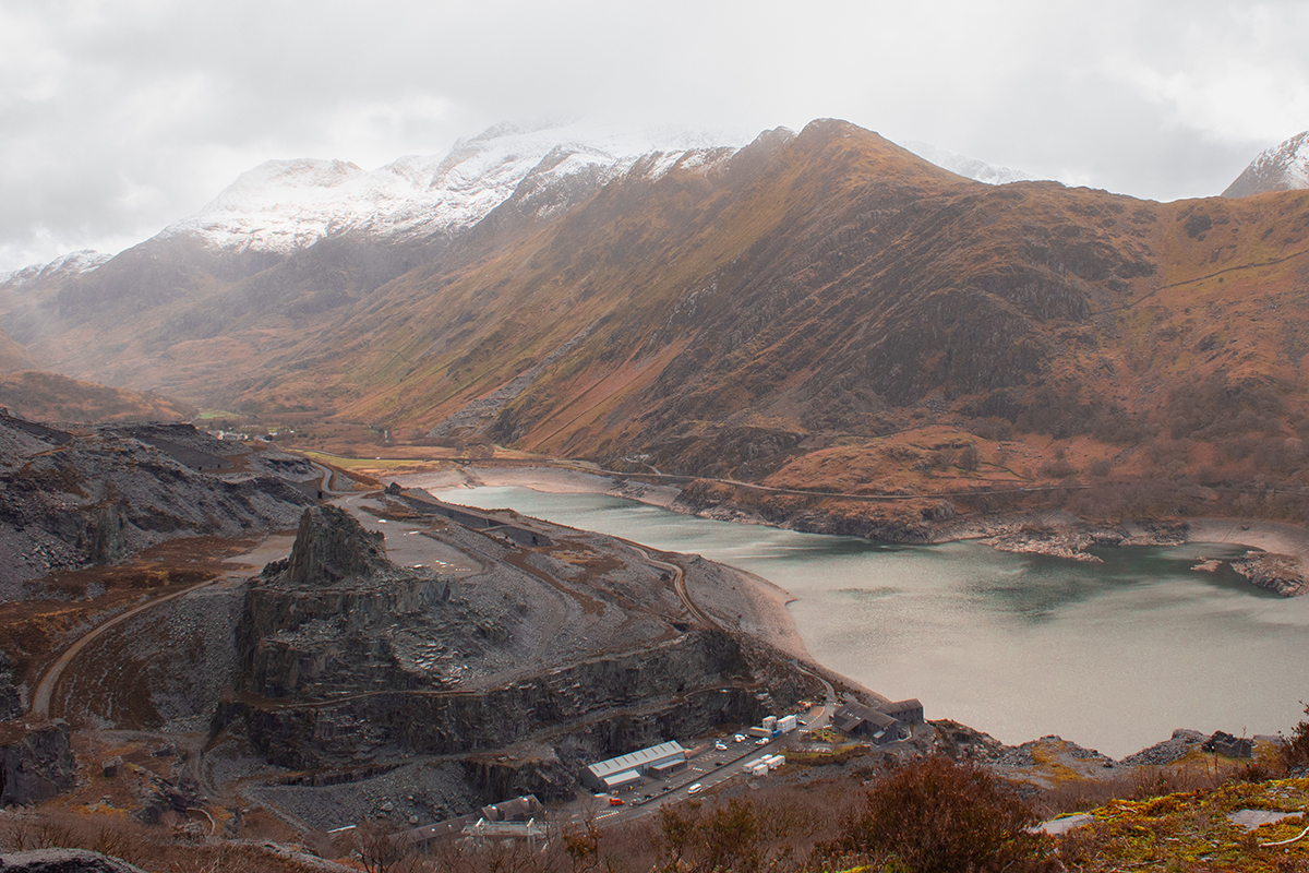 Landscape image with buildings, river and snow covered mountains
