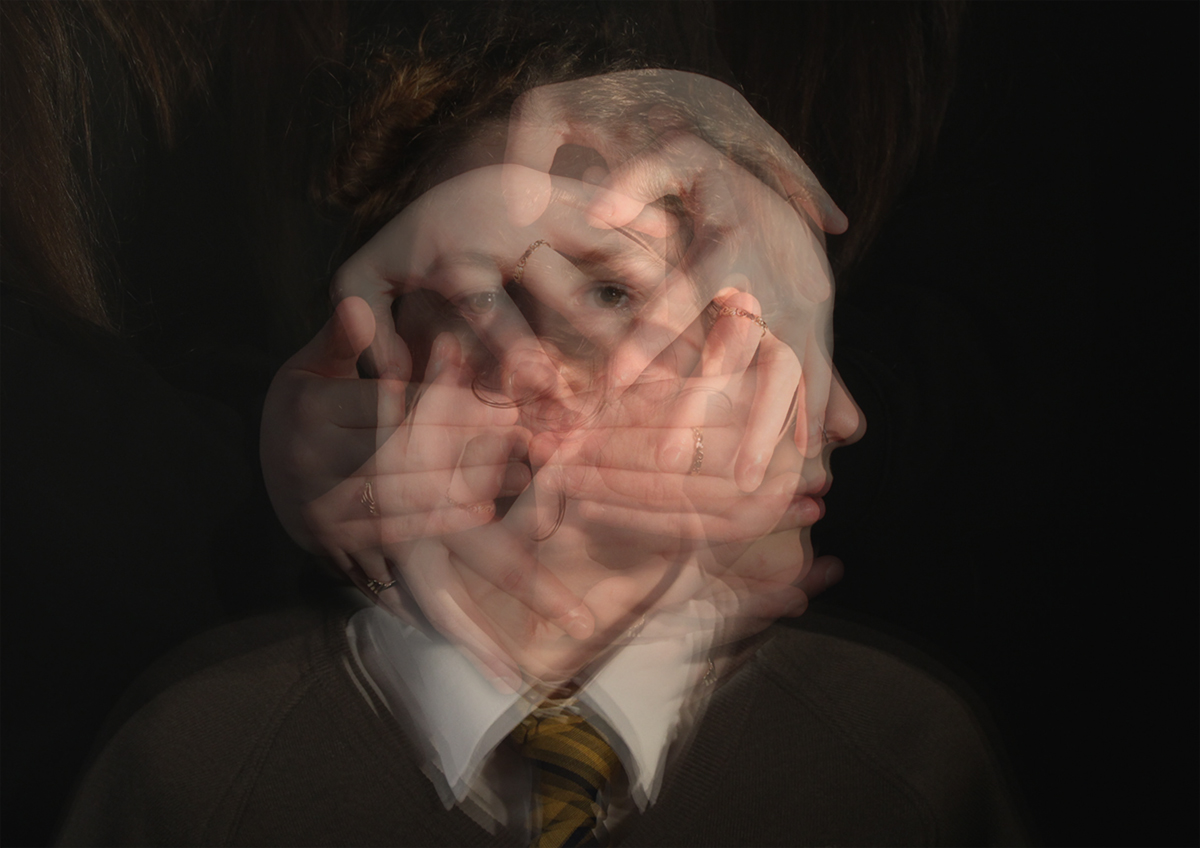 Image from exhibition showing blurred hands over a persons face.